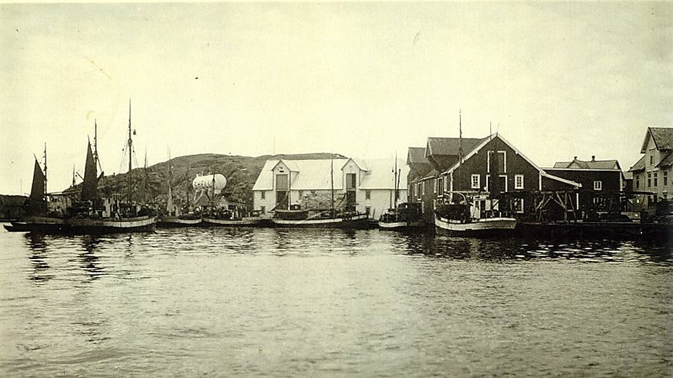 Historisk bilde i sort/hvitt: Nordnorsk fiskevær med synlig Shell-tank.