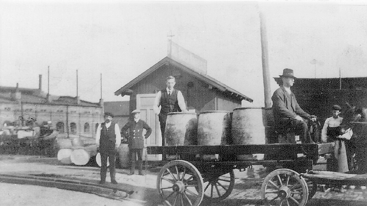 Historisk bilde i sort/hvitt: Frakt av lampeolje tønner med hest og kjerre."