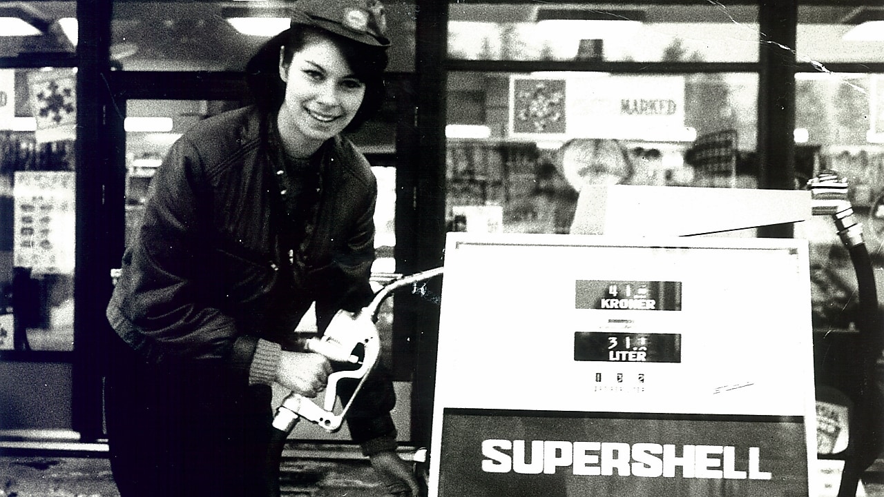 Historisk bilde i sort/hvitt: Smilende Shell-dame på en besninstasjon.