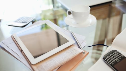 Tablet computer, newspaper, coffee cup and cell phone on desk