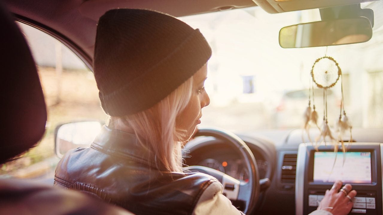Ung kvinne sjekker instruksene som vises på den innebygde navigasjonsskjermen i bilen hennes